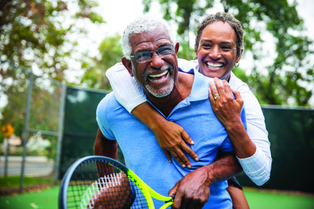 Senior Black Couple on Tennis Court Piggyback A senior black couple piggyback together on the tennis court.
